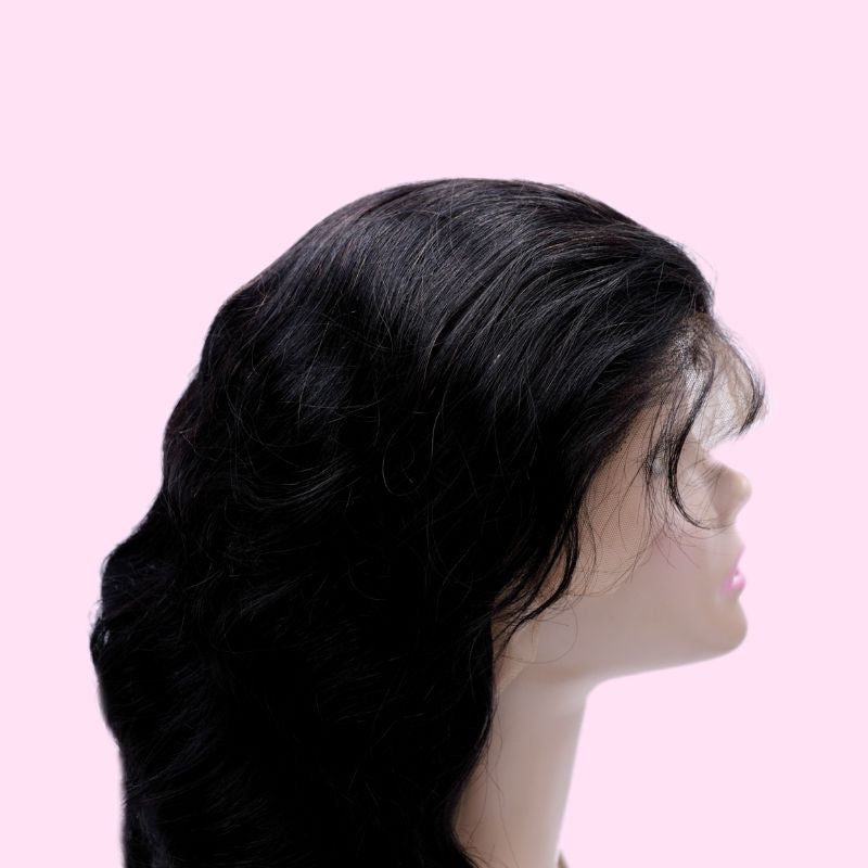 Body wave natural black human hair wig on a mannequin against a pink background seen from the side with waves shaping the length