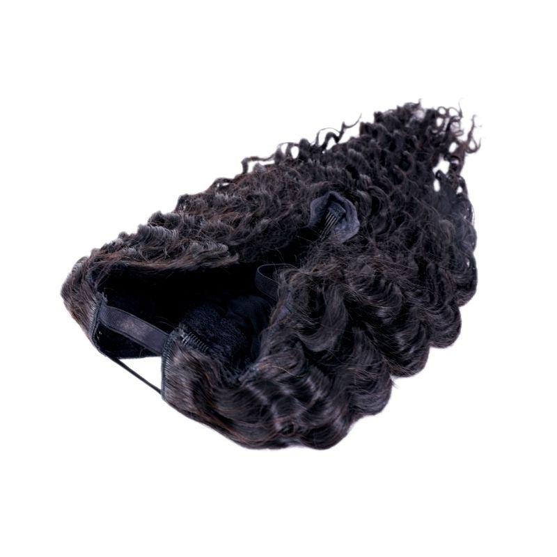 Natural black deep wave human hair wig laid on its side on a white background showing the cap edge and a snap clip
