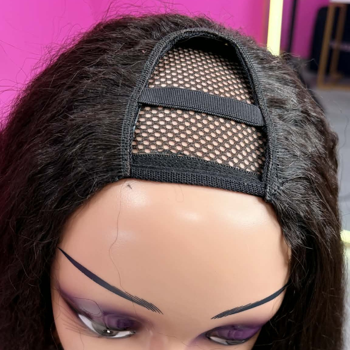Top-down view of mannequin wearing 12 inch kinky straight u-part human hair wig showing mesh u-part opening and clip bands
