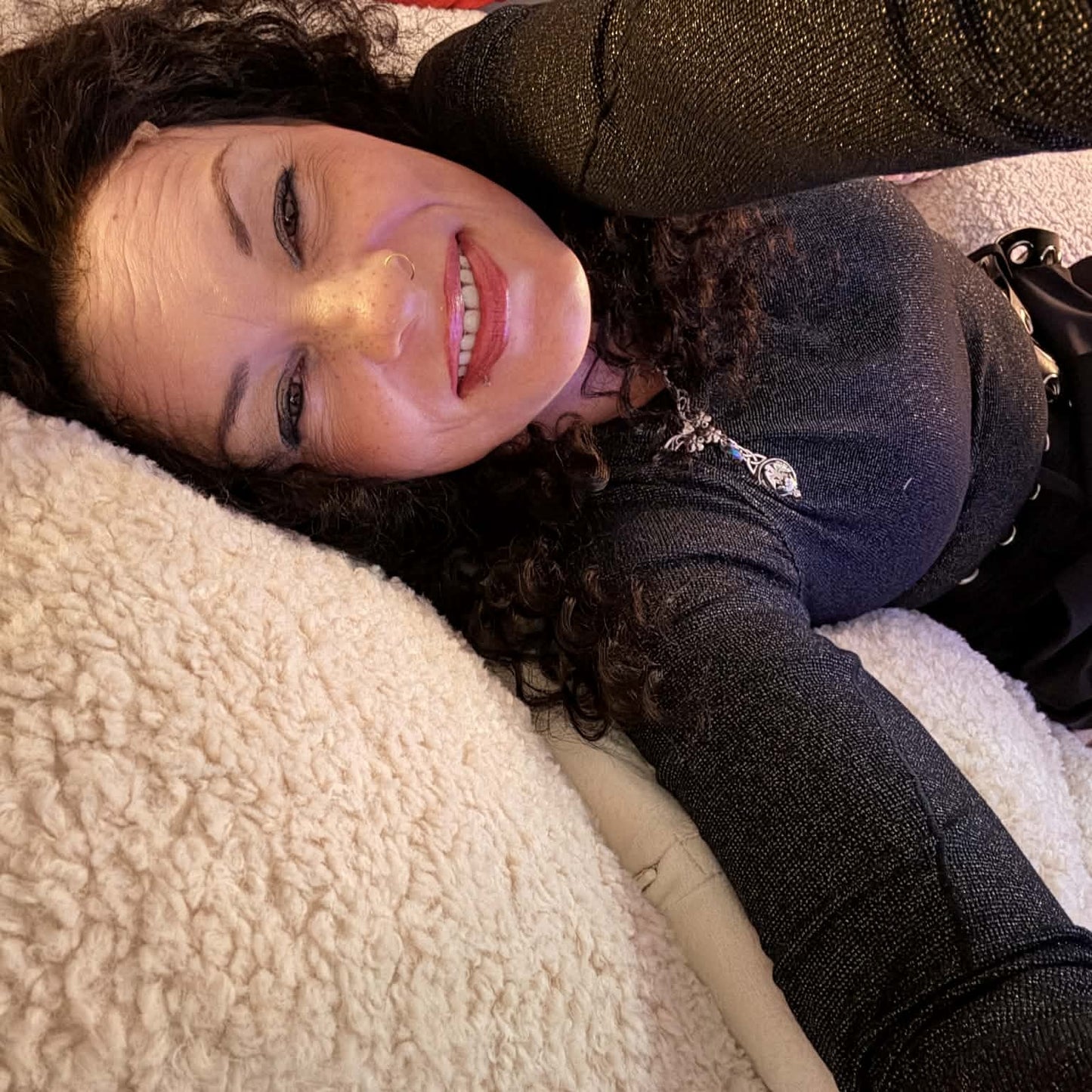 Lifestyle photo lying down wearing 22 inch deep wave lace front human hair wig showing curls spread naturally on blanket