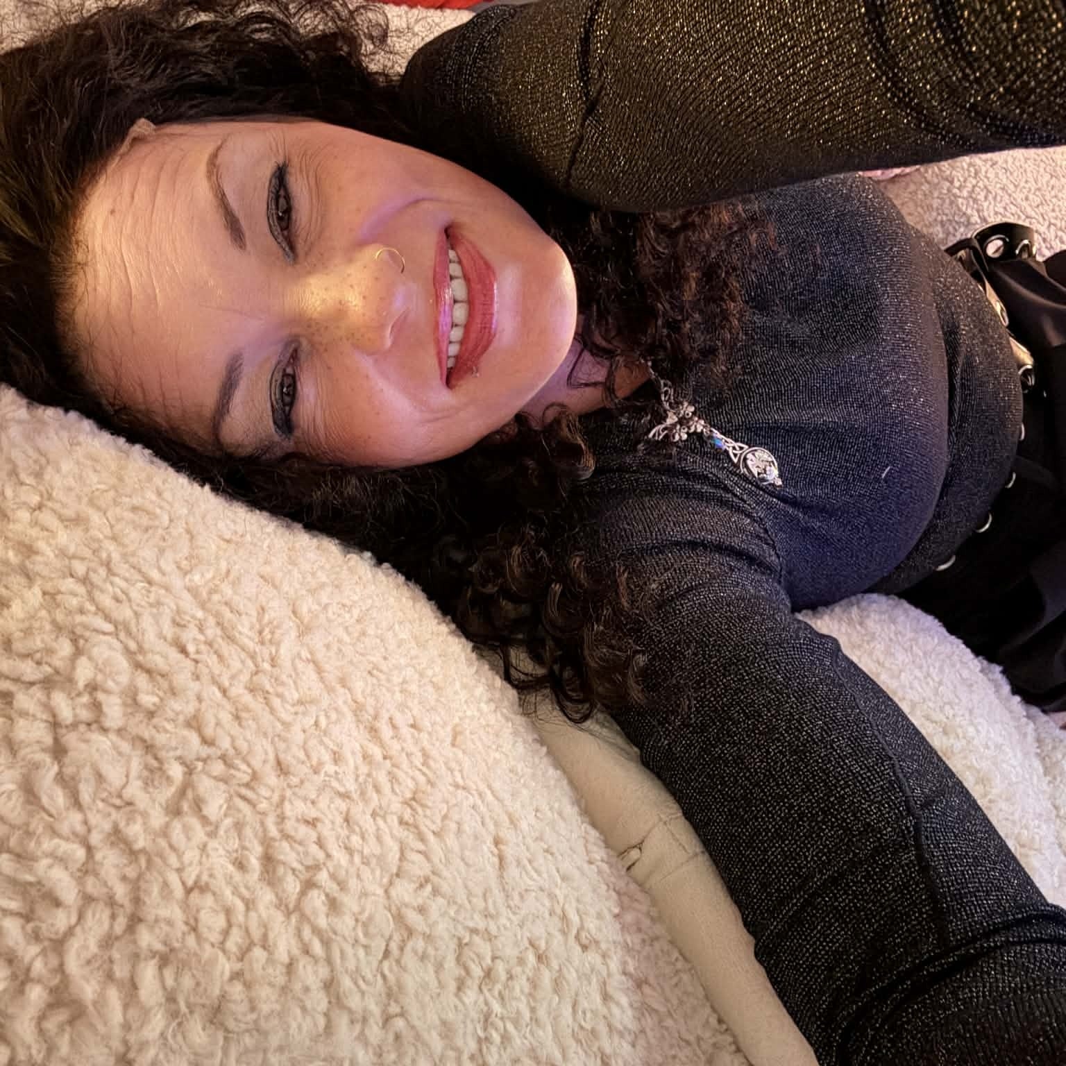 Lifestyle photo lying down wearing 22 inch deep wave lace front human hair wig showing curls spread naturally on blanket