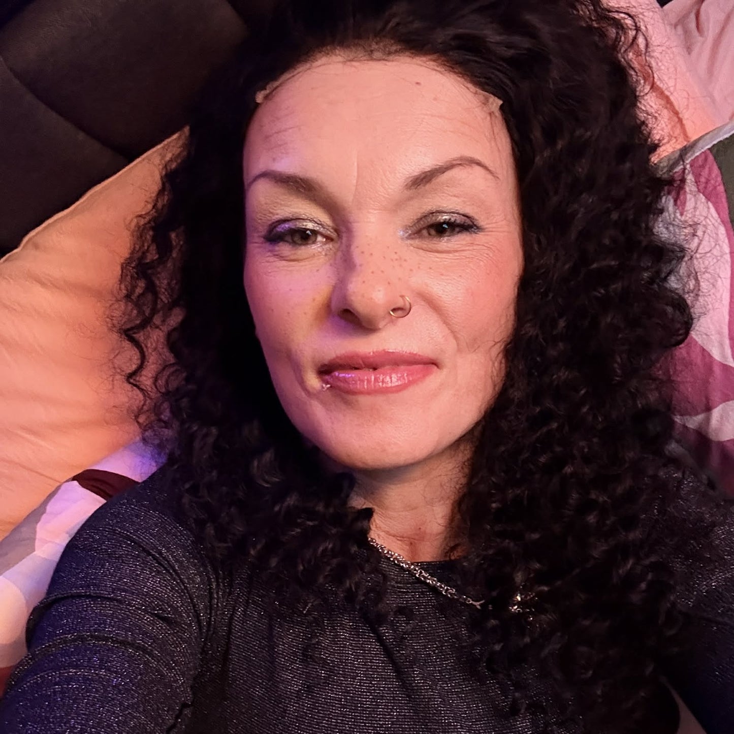 Reclined selfie wearing 22 inch deep wave lace front human hair wig showing curls spread on pillow with relaxed styling