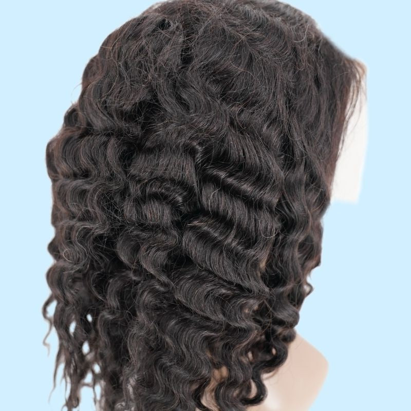 Close view of the back of a natural black deep wave human hair wig on a blue backdrop showing the wave pattern and the lace edge