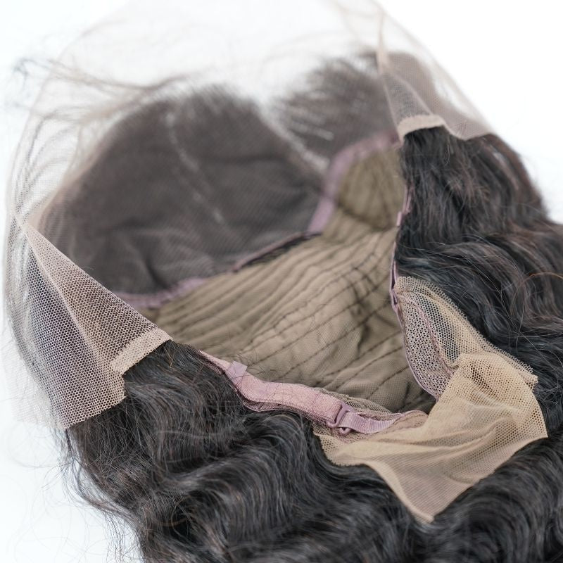 Interior of a natural black deep wave human hair wig showing the lace front panel from the underside and the stitched wefts on the cap