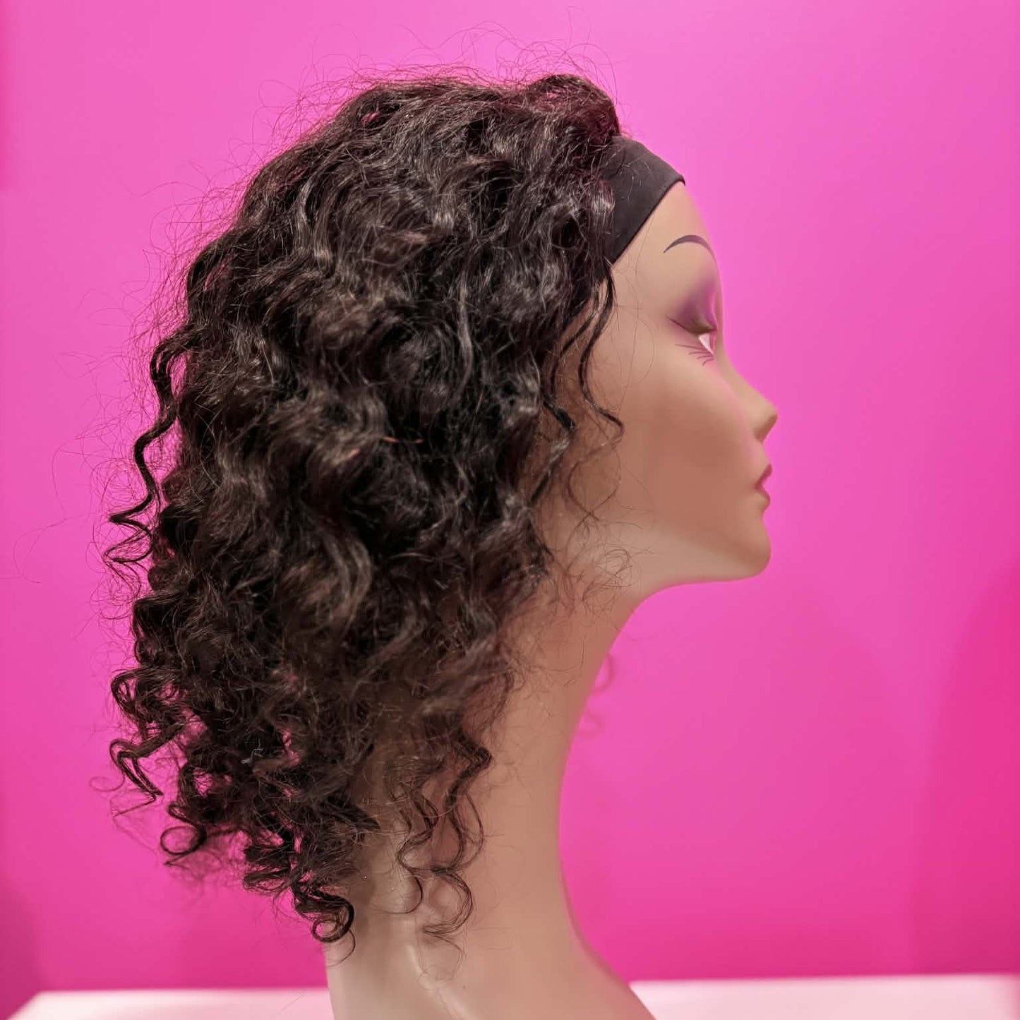 Left side profile of 14 inch deep wave headband human hair wig in natural black on mannequin showing headband and natural curl movement