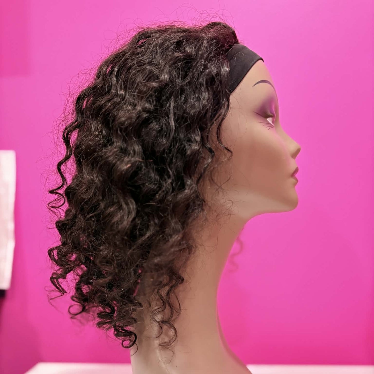 Right side profile of 14 inch deep wave headband human hair wig in natural black on mannequin showing headband and curl length