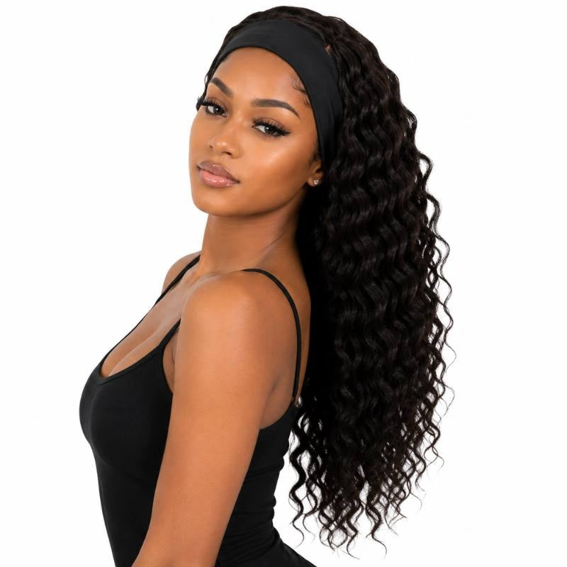 Model at an angle wearing a natural black deep wave human hair wig with the headband in place and waves swept over one shoulder