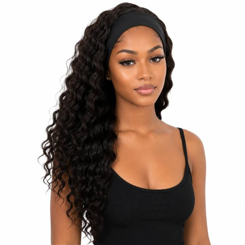 Model wearing a natural black deep wave human hair wig with the attached black headband across the forehead and waves past the chest