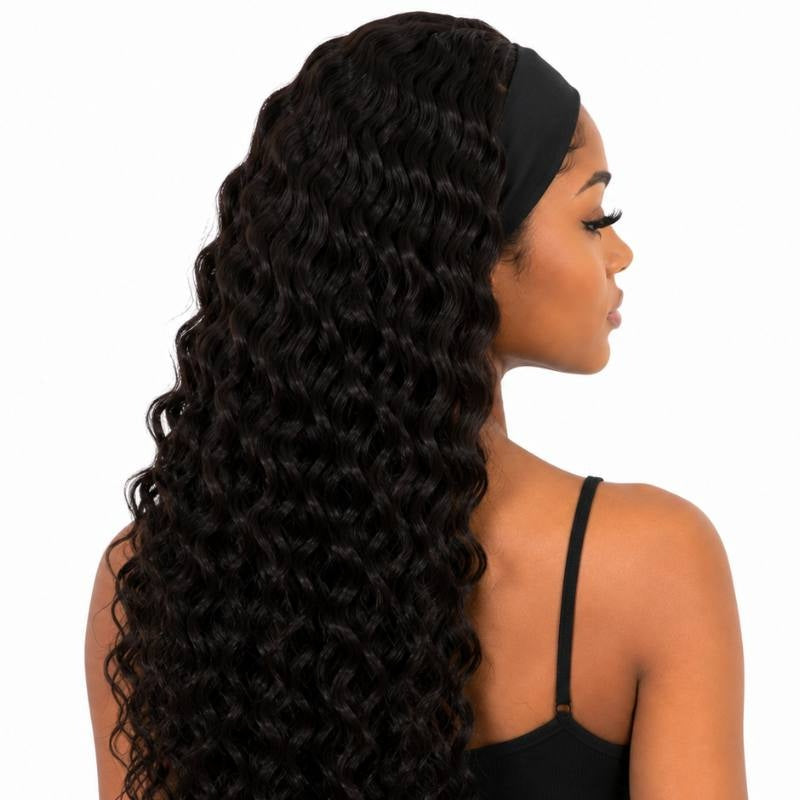 Rear three quarter view of a model wearing a natural black deep wave human hair wig with the headband visible and curls down the back