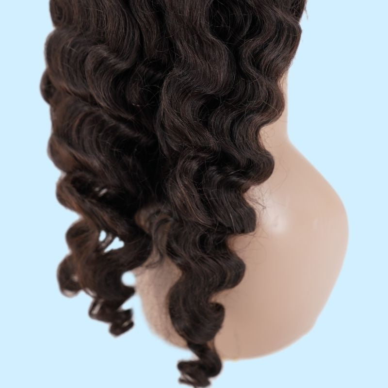 Close-up of a natural black loose wave human hair wig on a mannequin against a pale blue background showing the spiral wave through the ends