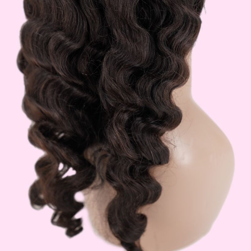 Close-up of a natural black loose wave human hair wig on a mannequin against a pink background showing defined waves down the length