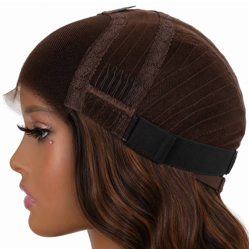 Side of a body wave human hair wig cap on a mannequin showing a comb above the ear, the elastic band and balayage streaks in the hair below
