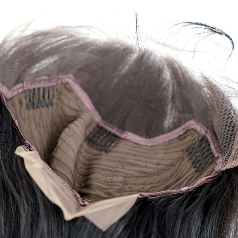 Looking into the open cap of a natural black straight human hair wig showing the underside of the lace, three combs and the adjustable strap