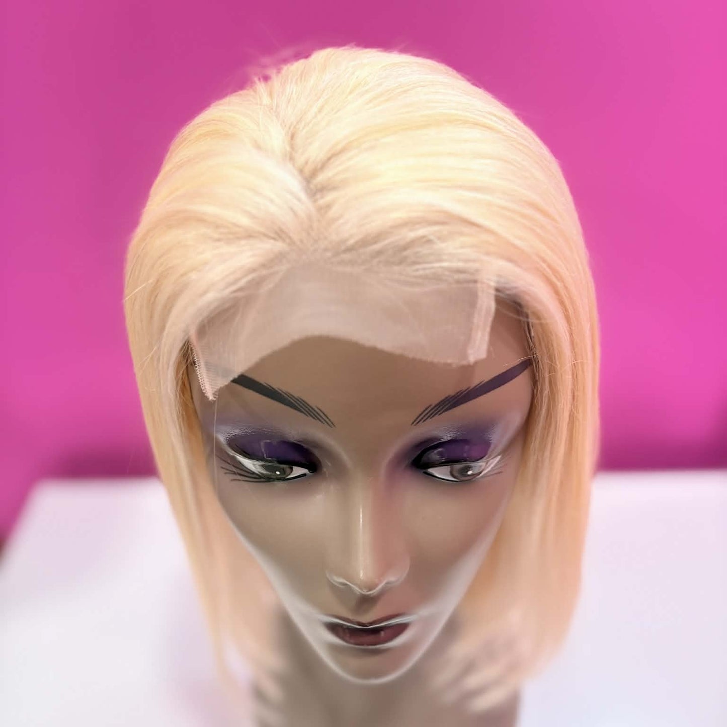 Top-down view of 10 inch blonde straight bob human hair wig showing lace closure parting and straight hair texture