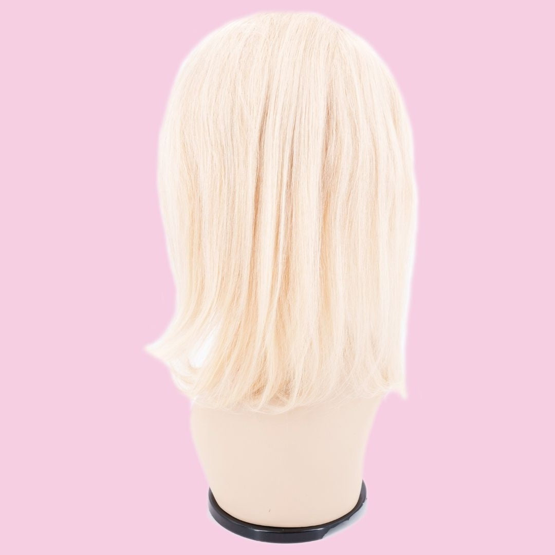 Back of a blonde straight bob human hair wig on a mannequin head against a pink background showing the blunt cut ends