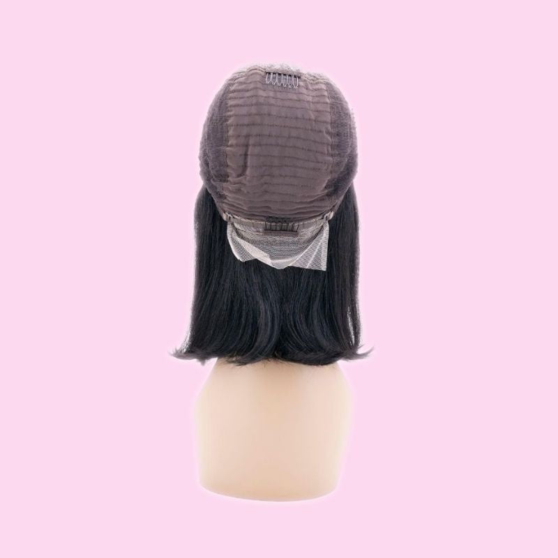 Natural black straight bob human hair wig turned inside out on a stand against a pink background showing the cap, crown comb and lace panel