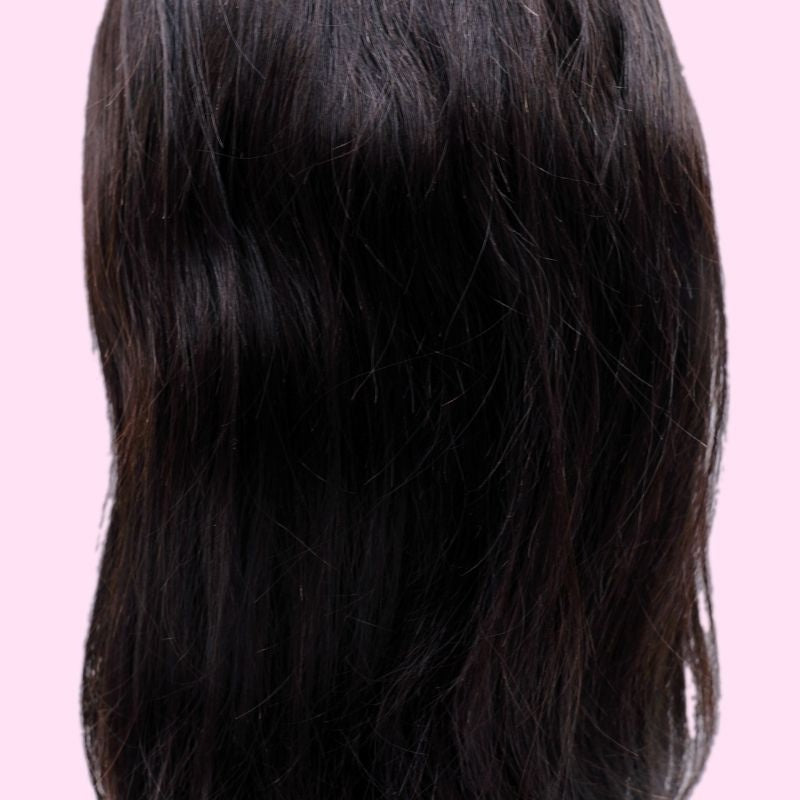 Close crop of the back of a natural black straight human hair wig against a pink background showing the length and surface texture