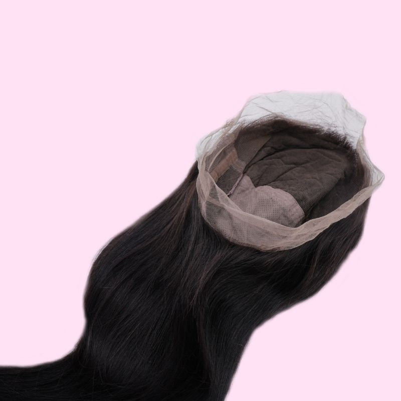Natural black straight human hair wig laid on a pink background showing the open cap and the lace edge running around the perimeter