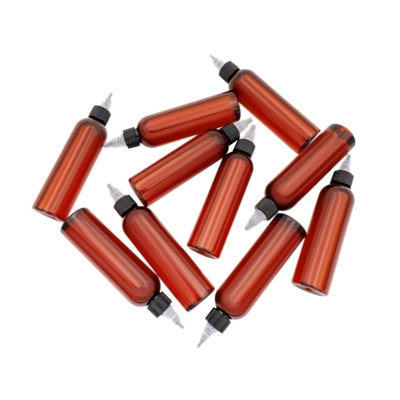 Group of amber plastic bottles with black pointed applicator caps scattered on white, the scalp serum sold with hair extensions and wigs