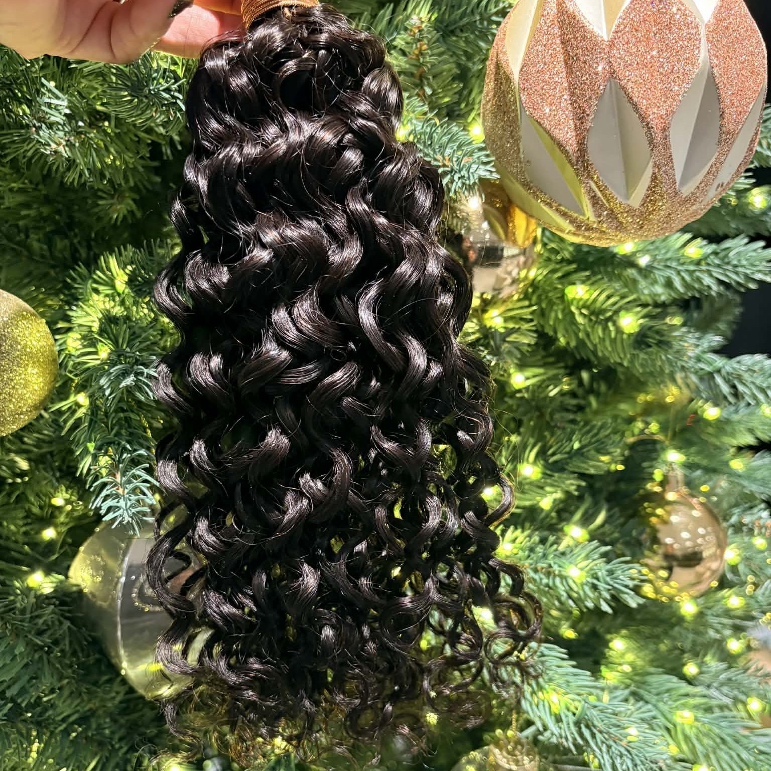 16 inch ocean wave sew-in hair extensions bundle held up showing loose flowing wave pattern with weft track and rubber band securing