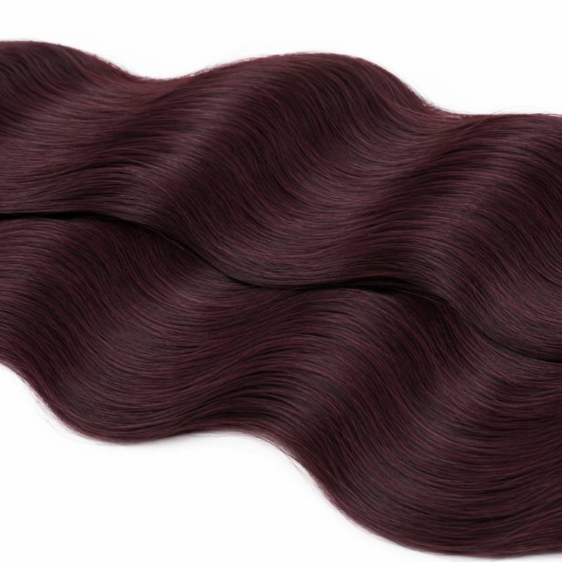 Macro crop of the S shaped wave pattern in burgundy 99J body wave sew-in hair extensions laid across a white surface