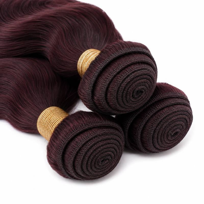 Close-up of the coiled wefts and gold bands on three bundles of burgundy 99J body wave sew-in hair extensions laid on white