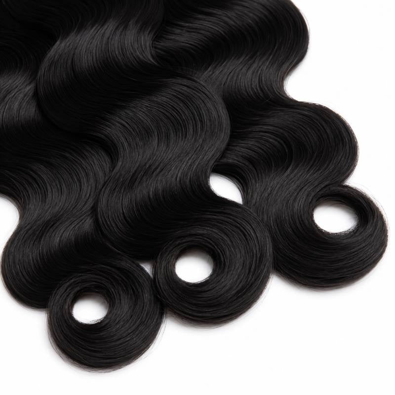 Angled crop of the curled ends on three bundles of jet black 1 body wave sew-in hair extensions laid on a white surface