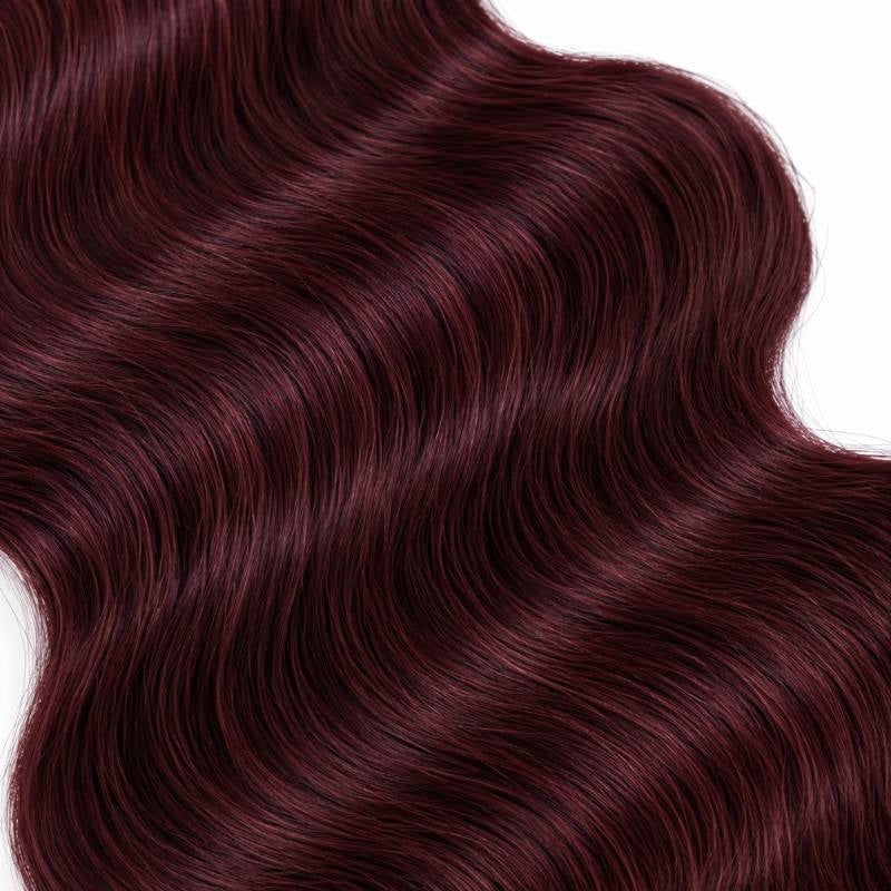 Macro crop of the wave pattern in burgundy 99J body wave sew-in hair extensions laid diagonally across a white surface
