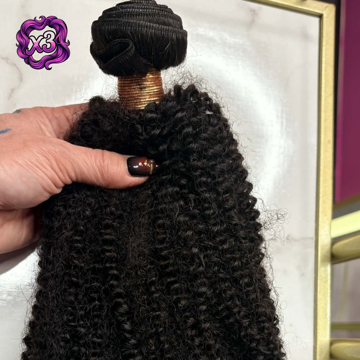 3 bundle deal — Hand holding 16 inch Brazilian afro kinky curly sew-in hair extensions bundle in gold frame showing dense coil texture and volume