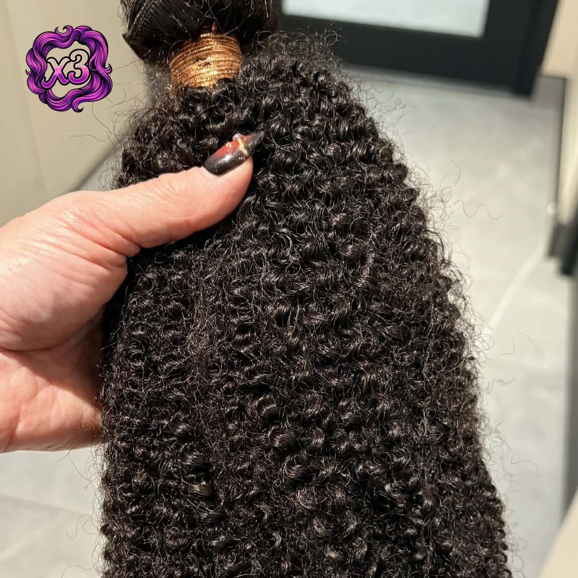 3 bundle deal — Hand holding 16 inch Brazilian afro kinky curly sew-in hair extensions bundle showing weft track at top and dense coil pattern