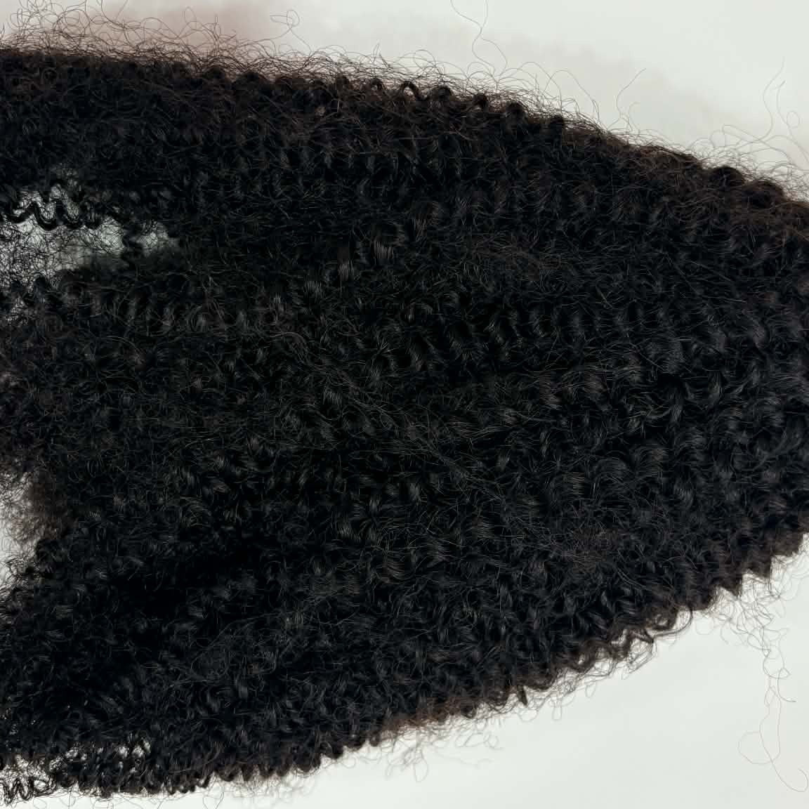 Close-up flat lay of 16 inch Brazilian afro kinky curly sew-in hair extensions bundle showing coil texture detail and volume