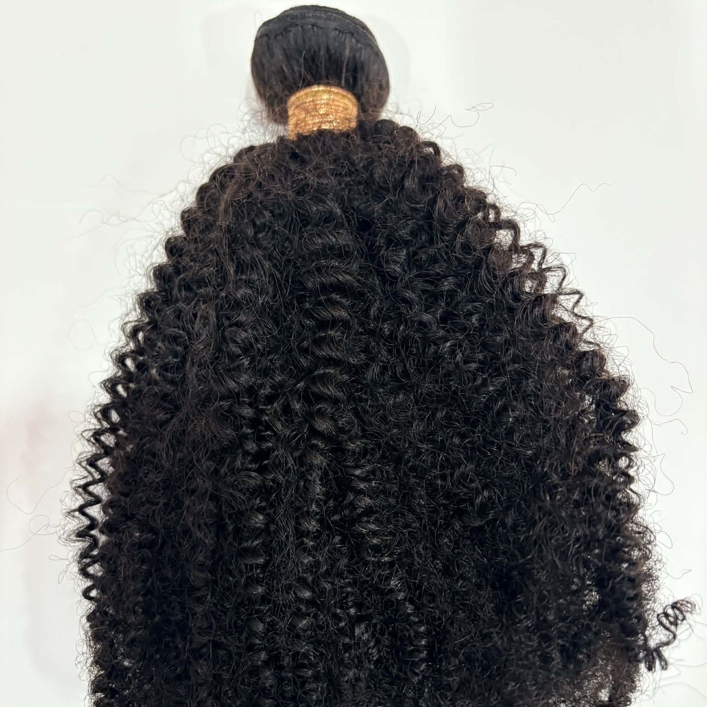 16 inch Brazilian afro kinky curly sew-in hair extensions bundle on white background showing full length from rubber-banded weft to coil tips