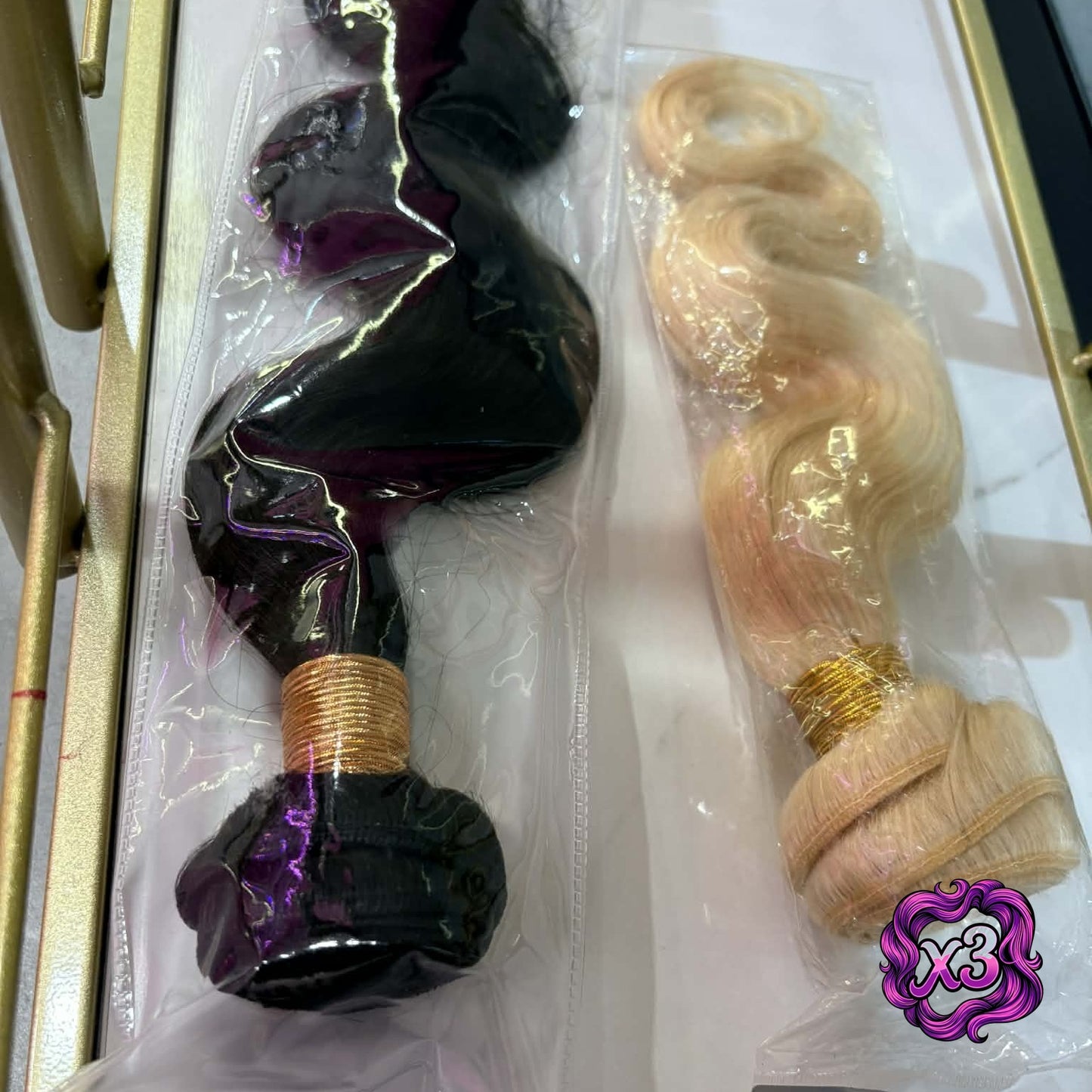 3 bundle deal — Two body wave sew-in hair extensions bundles in packaging inside gold frame showing natural black and blonde color options