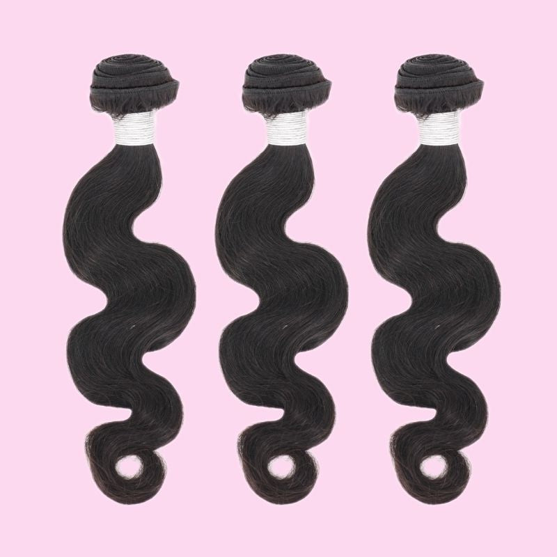 Three matching bundles of natural black body wave sew-in hair extensions on a pink backdrop with white thread wrapped below each folded weft