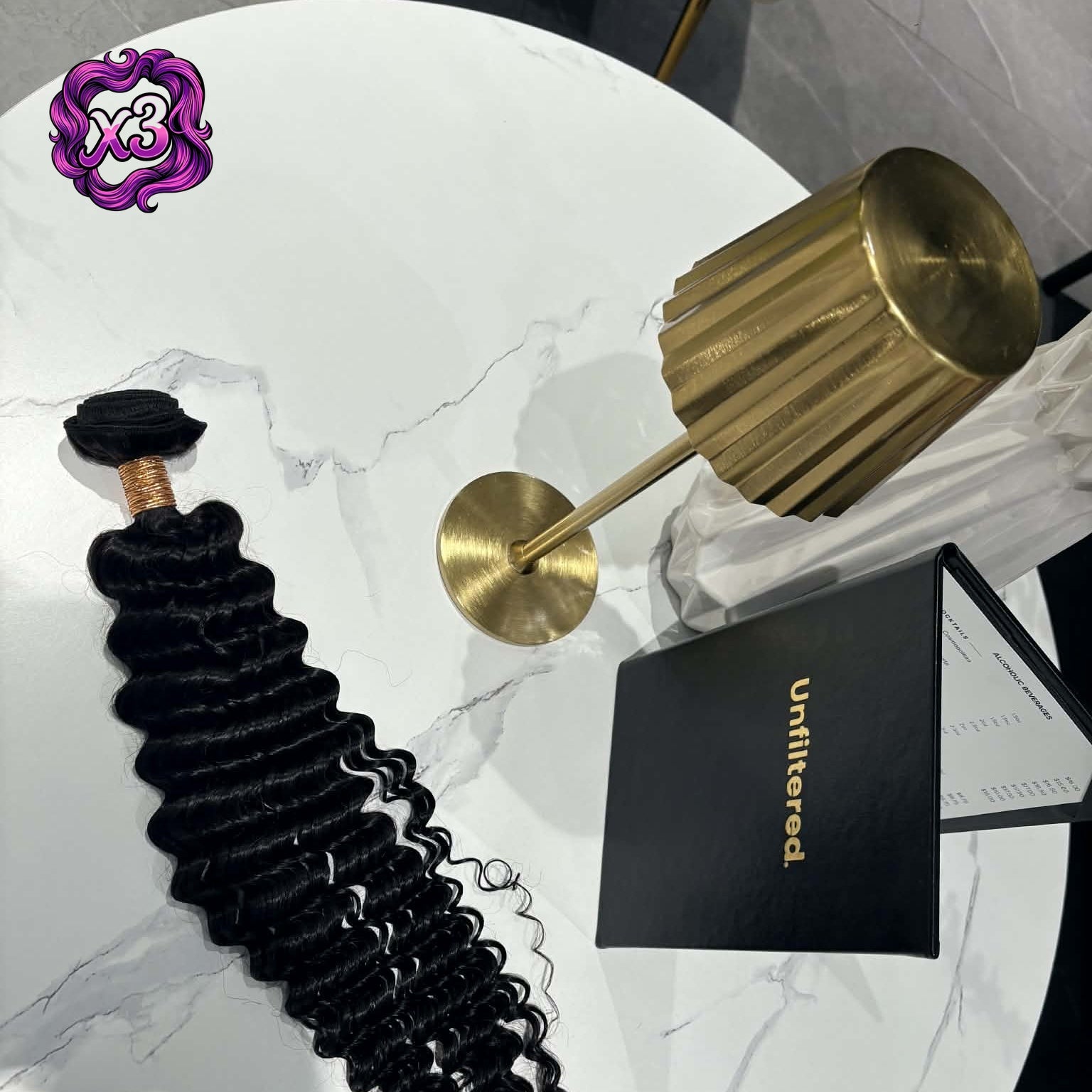 3 bundle deal — 16 inch Brazilian deep wave sew-in hair extensions bundle on marble table with gold lamp and brand card showing weft and spiral curls