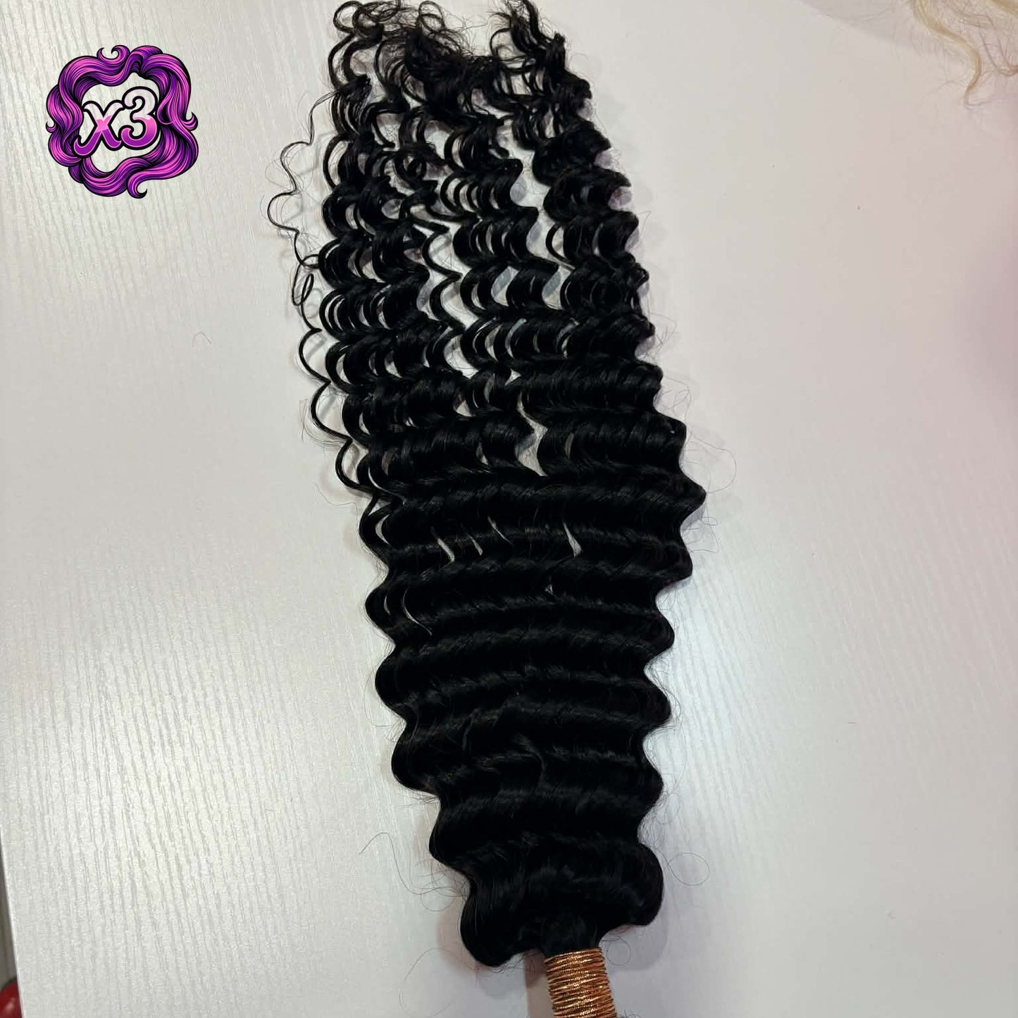 3 bundle deal — 16 inch Brazilian deep wave sew-in hair extensions bundle on white surface showing rubber-banded weft and spiral curl pattern