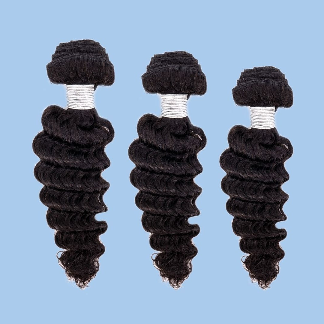 Three bundles of natural black deep wave sew-in hair extensions in graduated lengths on a blue backdrop with white thread wraps