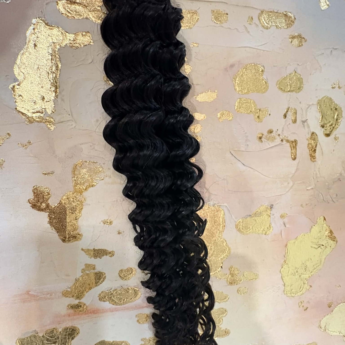 16 inch Brazilian deep wave sew-in hair extensions bundle on pink and gold surface showing spiral curl definition and natural shine