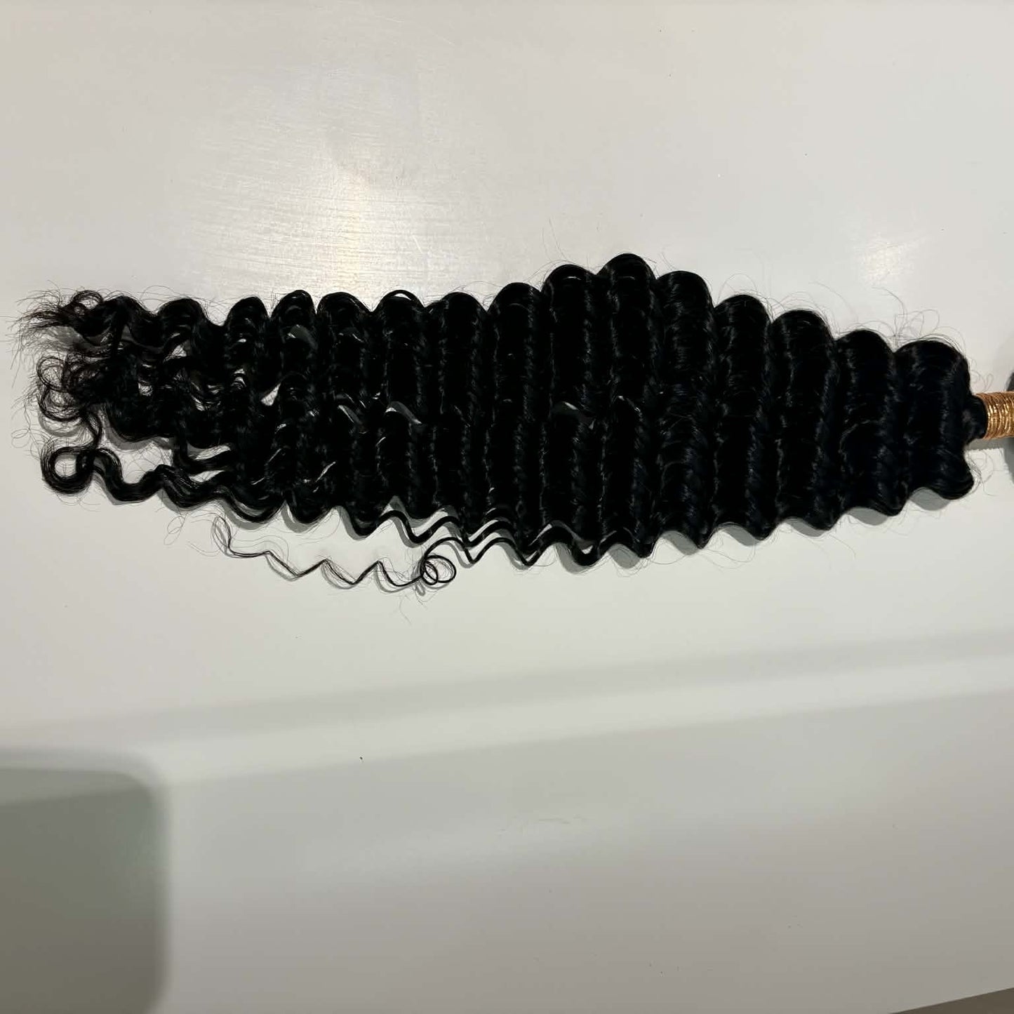 16 inch Brazilian deep wave sew-in hair extensions bundle flat lay on shelf showing full bundle length with defined S-spiral waves