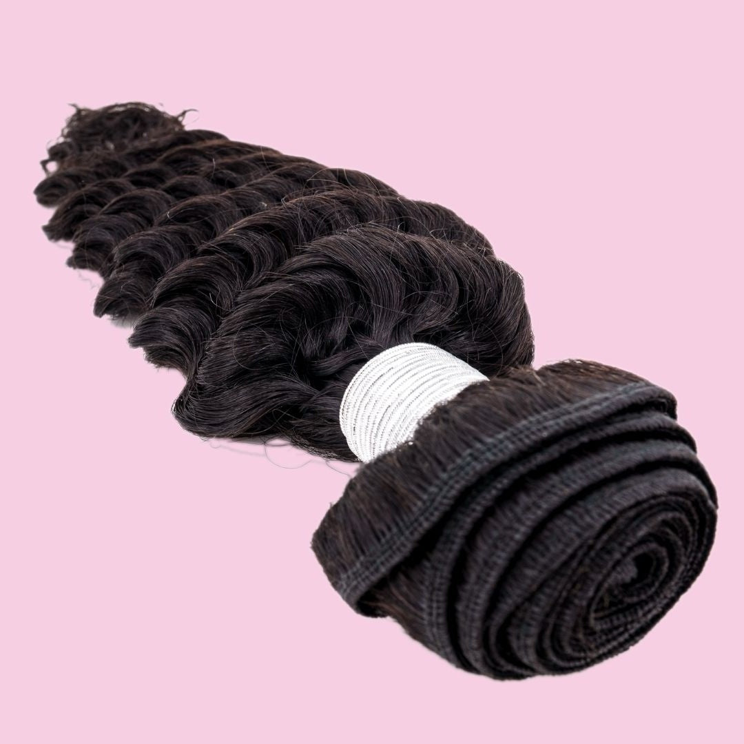 Natural black deep wave sew-in hair extensions on a pink backdrop with the rolled weft turned toward the camera and white thread wrap