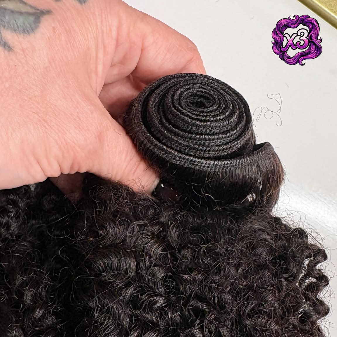 3 bundle deal — Close-up of 16 inch Brazilian kinky curly sew-in hair extensions weft showing rolled machine-made weft stitching and curl texture