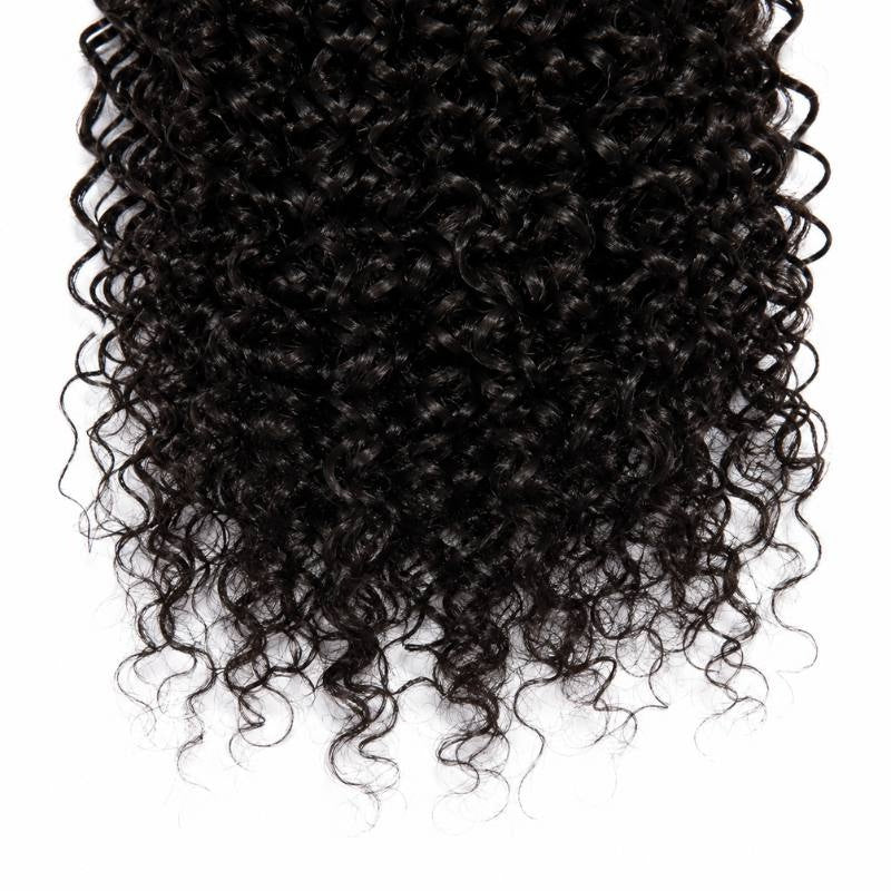 Close-up of the coiled ends of natural black kinky curly sew-in hair extensions showing the spring of the curls on a white background