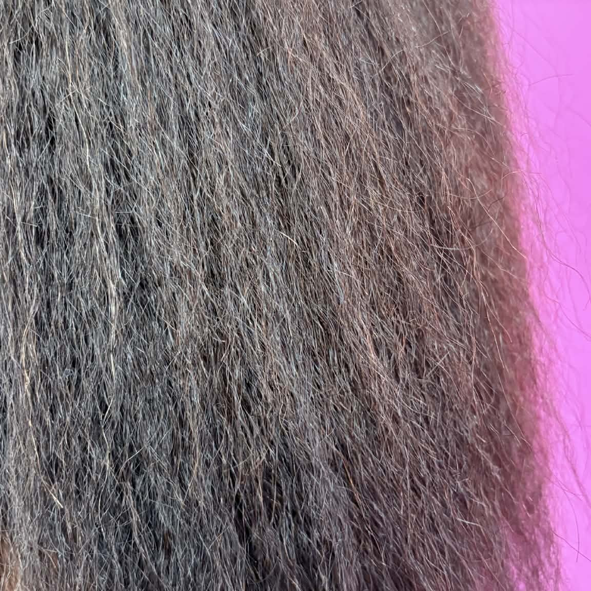 Macro close-up of 16 inch Brazilian kinky straight sew-in hair extensions texture showing natural kinks and blow-out pattern