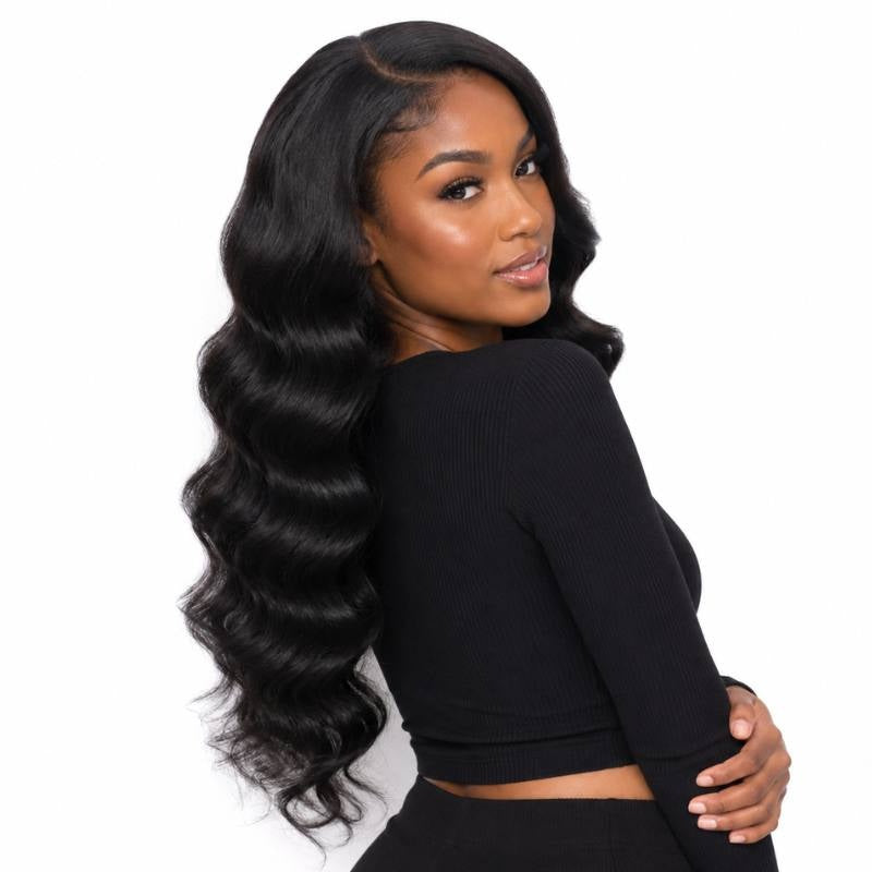 Model turned over her shoulder wearing long natural black loose wave sew-in hair extensions with a side part on a white background
