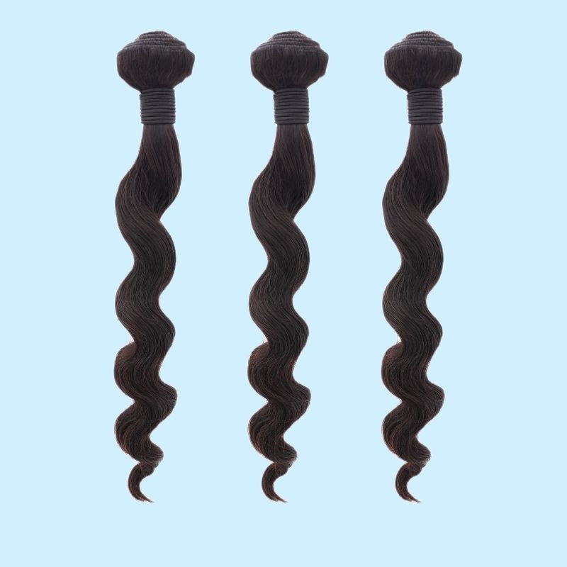 Three bundles of natural black loose wave sew-in hair extensions hanging in a row on a pale blue backdrop with thread wrapped wefts
