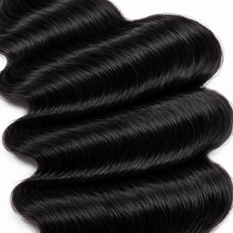 Macro close-up of natural black loose wave sew-in hair extensions showing the deep S-curves running across the frame on a white background