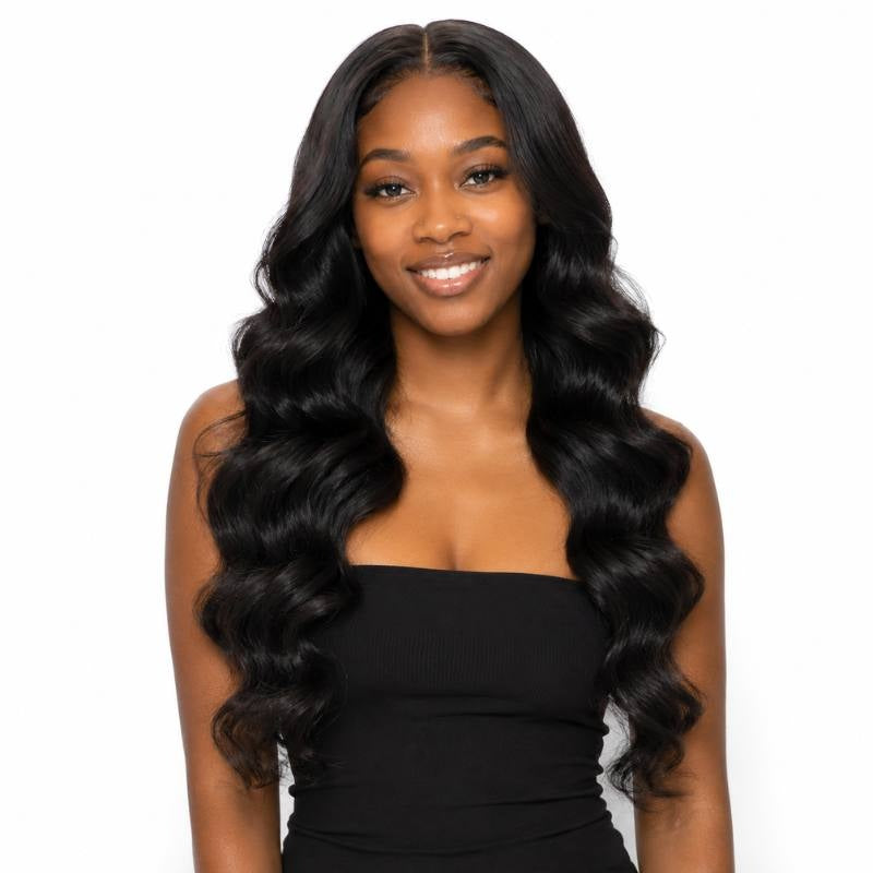 Model facing the camera and smiling while wearing long natural black loose wave sew-in hair extensions parted near the centre on a white background