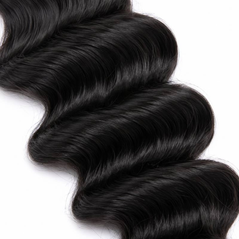 Macro close-up of natural black loose wave sew-in hair extensions showing the crest and trough of the wave pattern against a white background