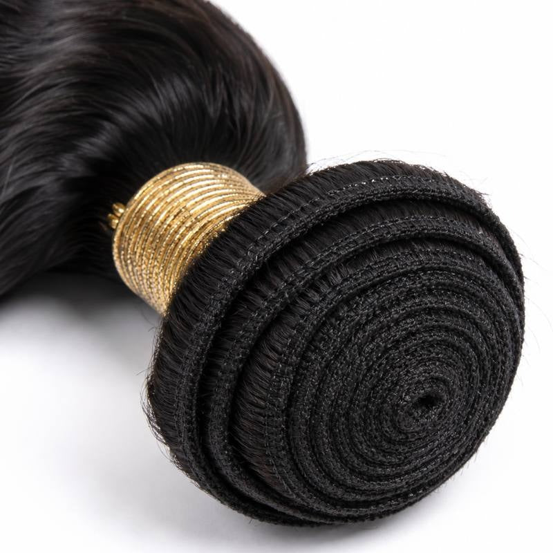 Macro view of the coiled weft on natural black loose wave sew-in hair extensions with a gold thread wrap and the stitched track spiralling inward