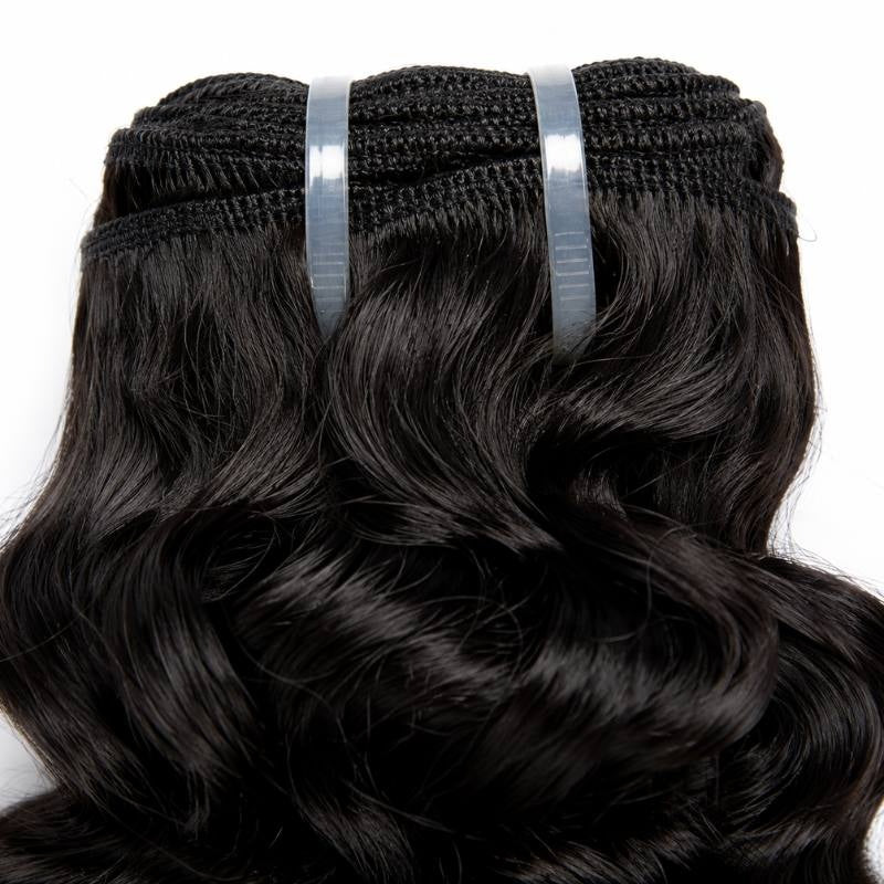 Close-up of the stitched weft track on natural black sew-in hair extensions held by two clear tape tabs above the wave pattern